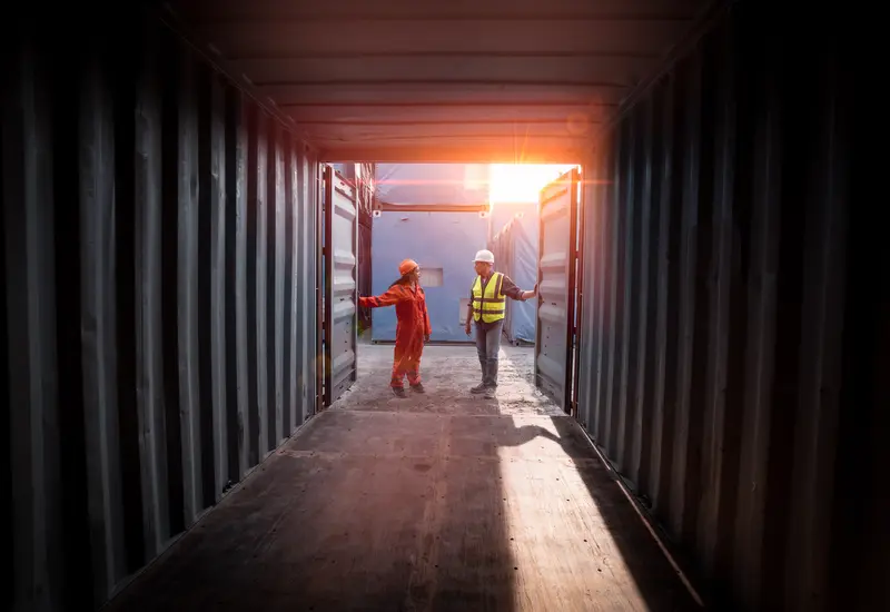 Two engineers inspecting a container from its open end