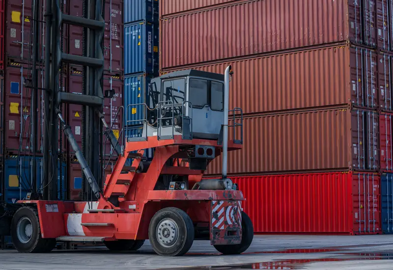 A reach stacker lifting a container in the yard